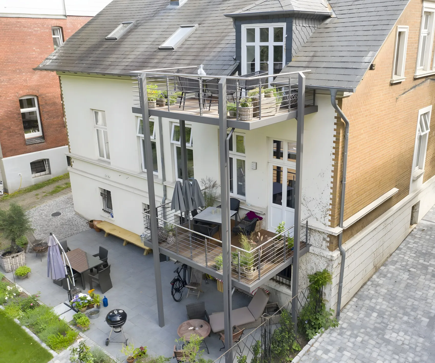 Altbauvilla mit angebauten Balkonen über zwei Etagen auf schlanken Stützen, von oben gesehen, darunter die Terrasse. Gebaut in Lüneburg.